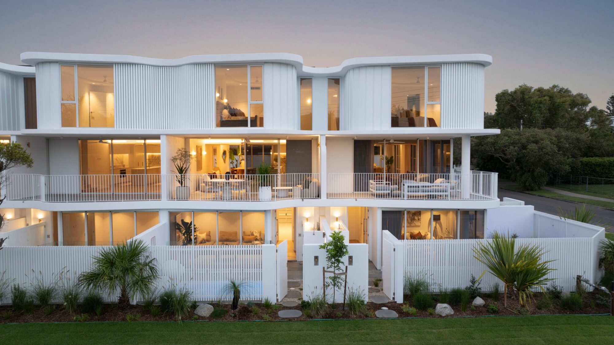 White three-storey townhouses with curved rooflines on Watson Street, Currimundi, at dusk
